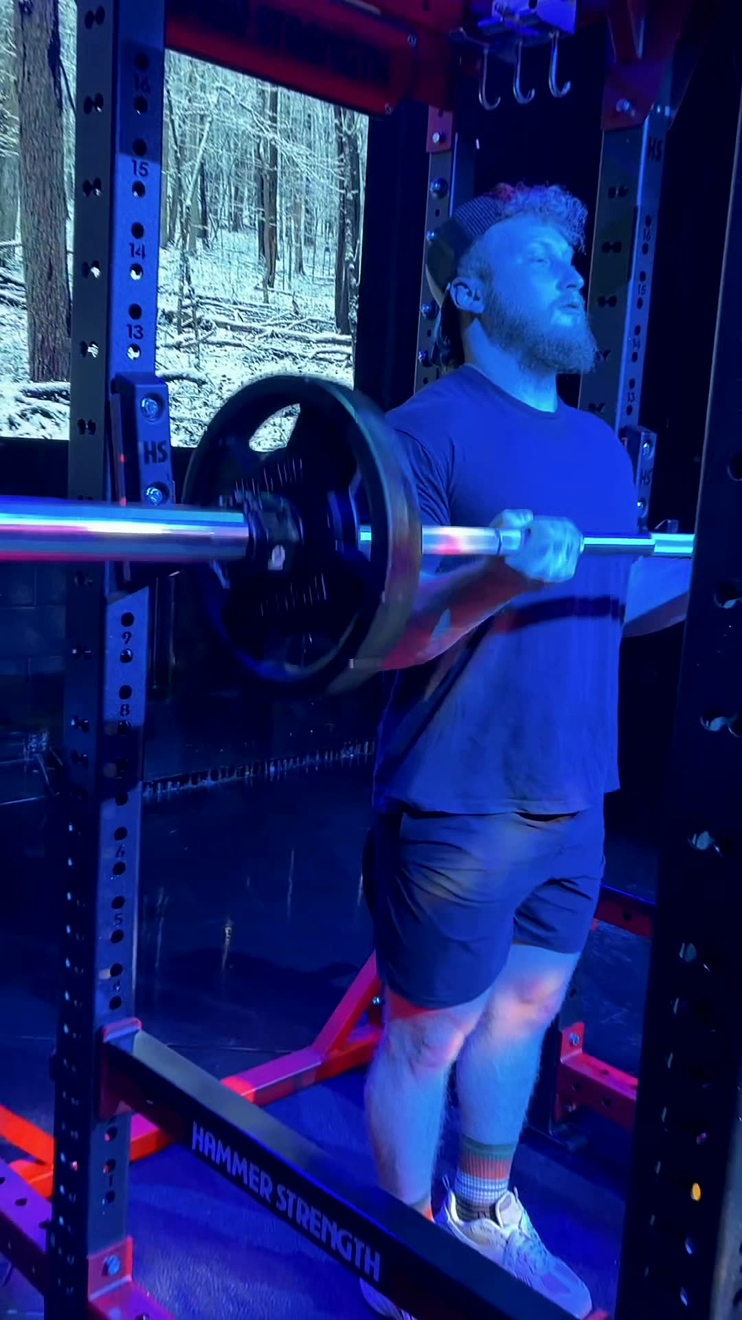 Loaded barbell in the rack with a snow-covered forest on the LED panel behind