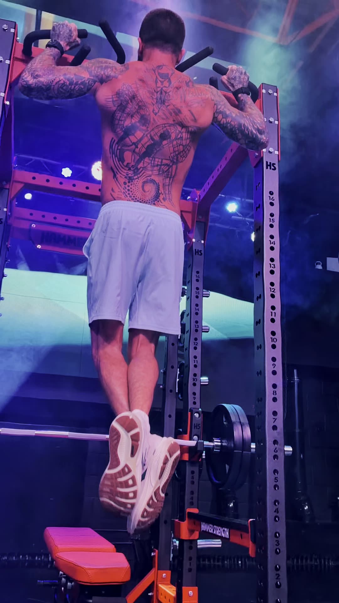 Full-body view of a pull-up in the rack, haze and coloured light behind
