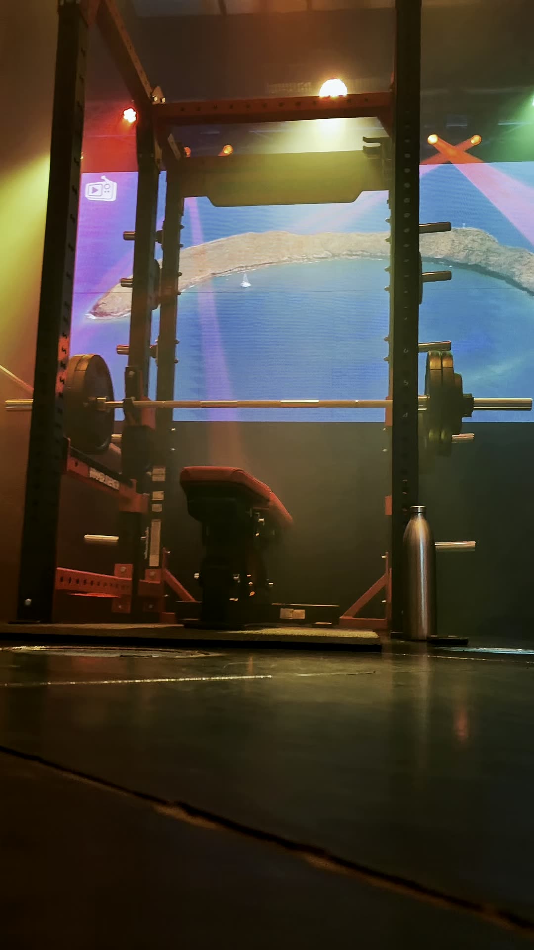 Hammer Strength rack in front of a wide illuminated LED panel on the polished training floor